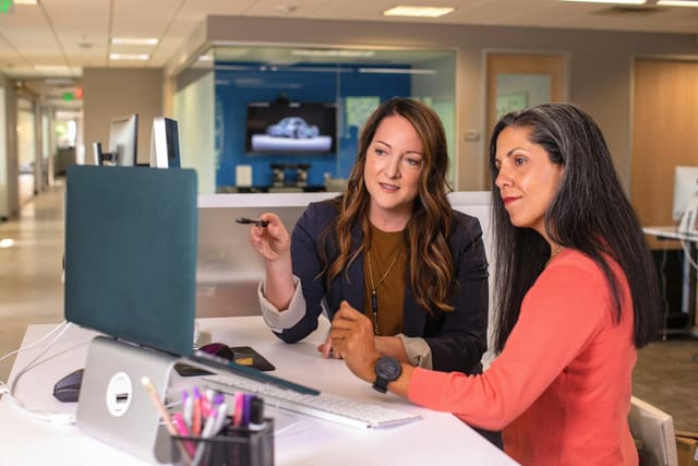 Twee collega's zitten samen achter een laptop